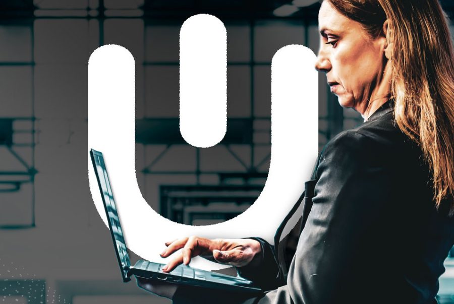 Professional working on a laptop in front of the Urbanise logo